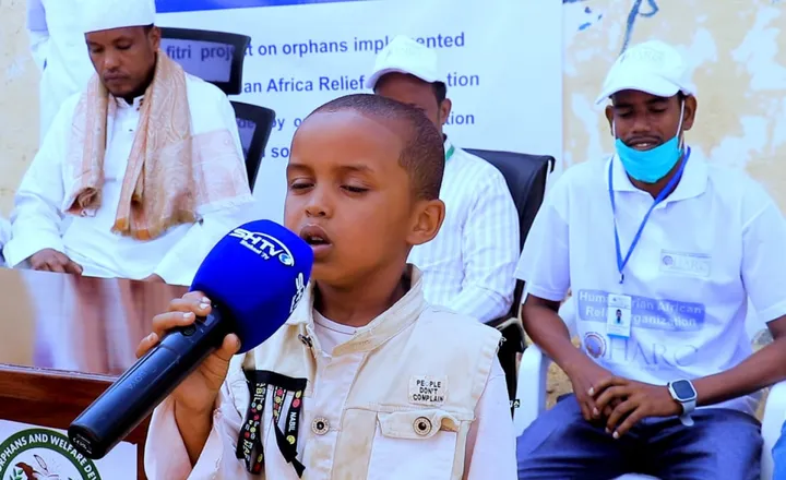 A boy speaks into a microphone at a HARO Eid al-Fitr event for orphans