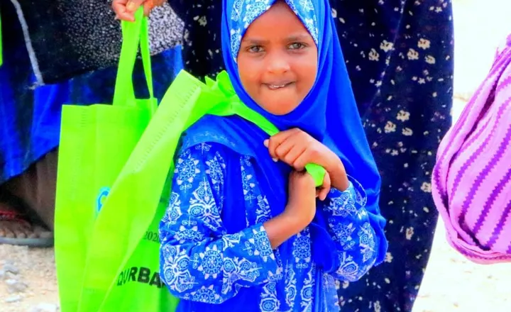 A smiling girl carries a HARO distribution bag over her shoulder