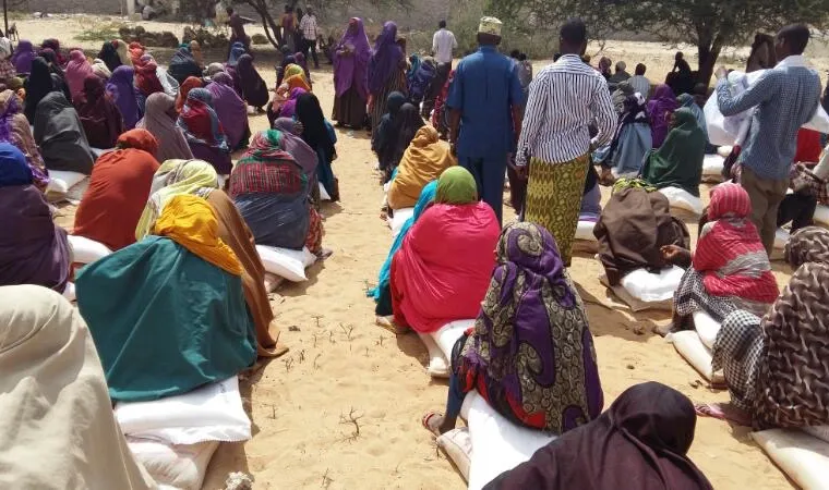 Women seated beside rows of rice sacks at the Geedlaawe camp food distribution, 2017