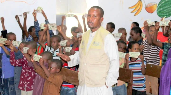 A HARO staff member distributes Eid cash gifts to a classroom of cheering children in Qardho, 2018
